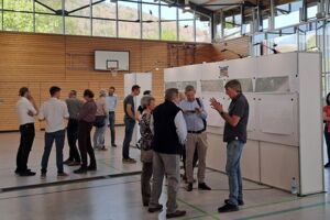 Mehrere Menschen unterhalten sich vor Infowänden
