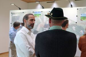 Personen unterhalten sich vor einer Karte auf einem Infomarkt