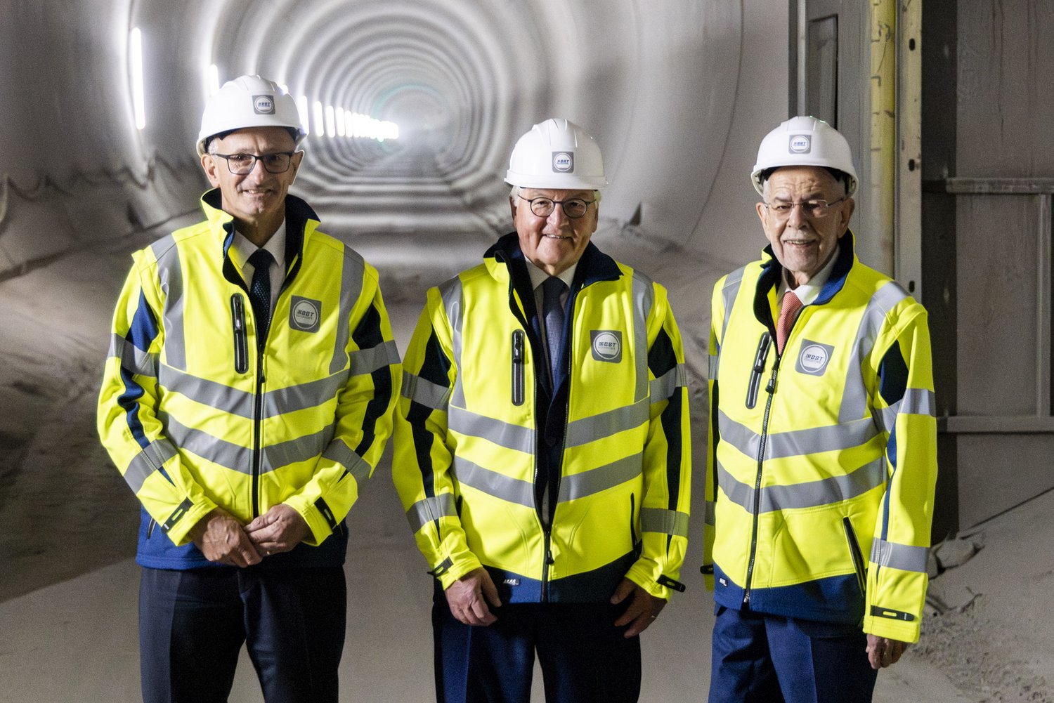 Tirols Landeshauptmann Anton Mattle, Deutschlands Bundespräsident Steinmeier und Österreichs Bundespräsident Van der Bellen stehen im Brenner-Basistunnel. Sie tragen Warnschutzjacken und Helme.